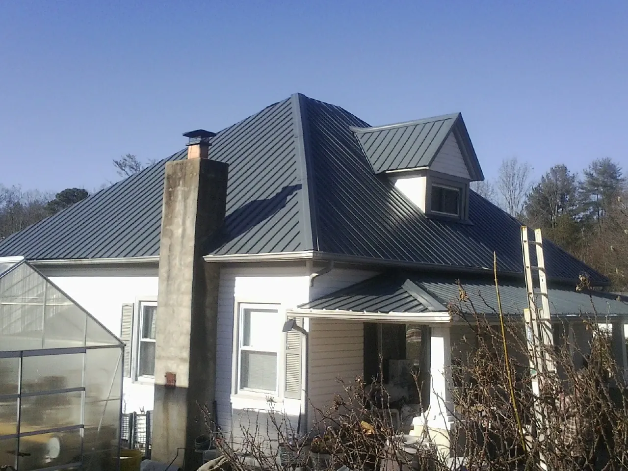 Dark blue standing seam metal roof on a white farmhouse with dormer — Slate & Tile Roof Repair by Roofing Brothers in Amity