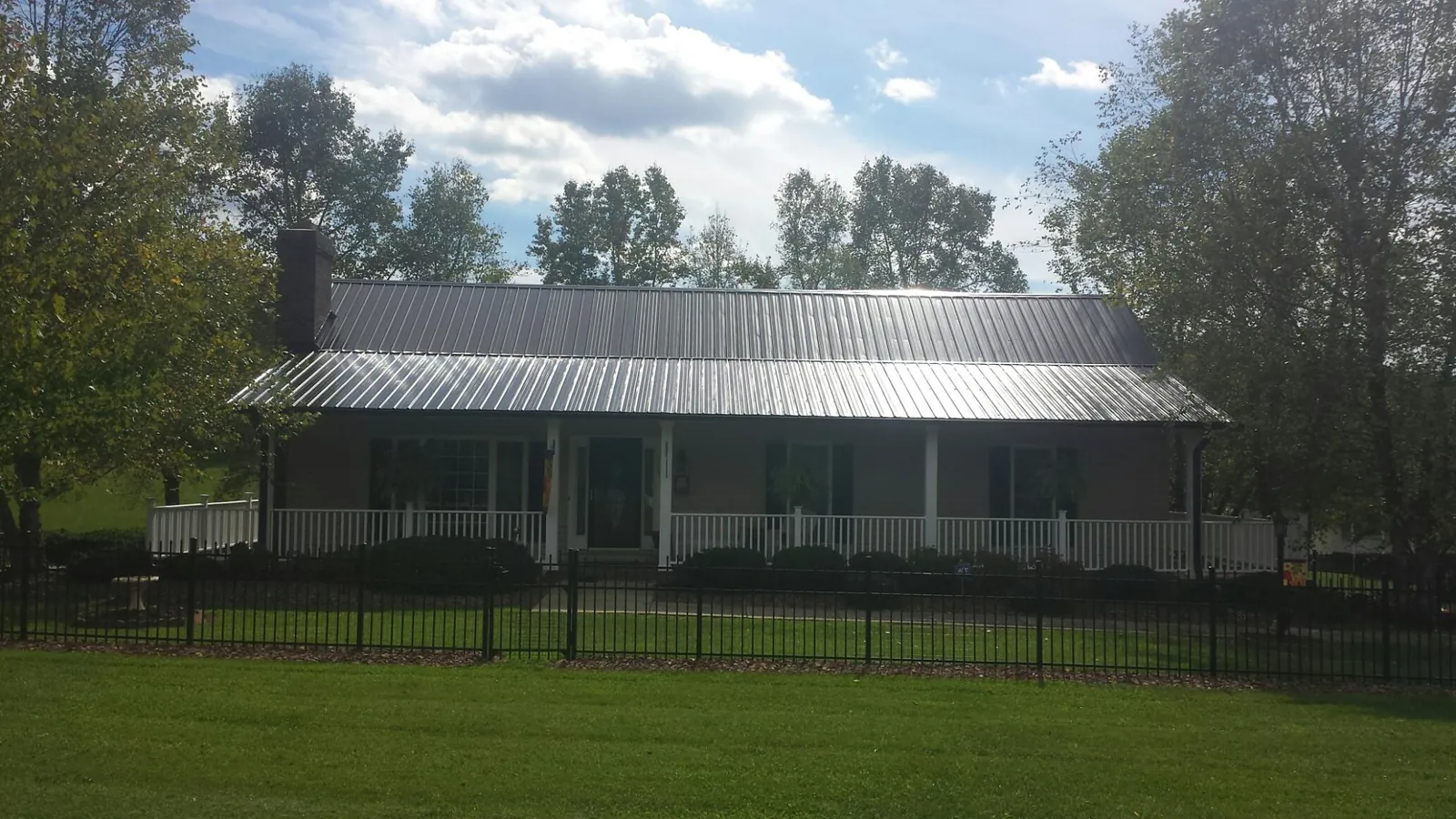Gray metal roof on a brick ranch with a full width front porch — Gutter Guard Installation work by our crew in Amity